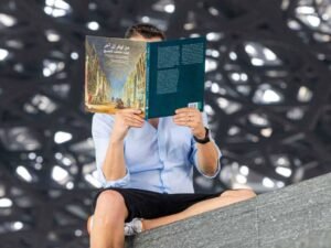 A person reading a book at the Louvre, symbolizing creativity and vision.