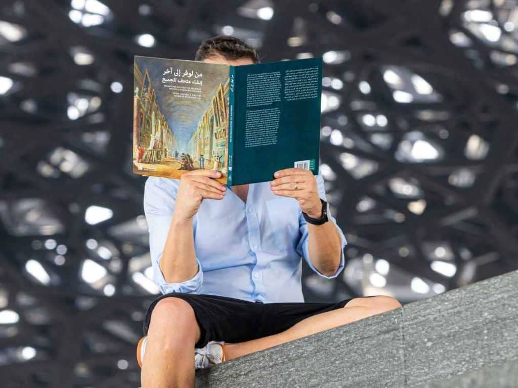 A person reading a book at the Louvre, symbolizing creativity and vision.